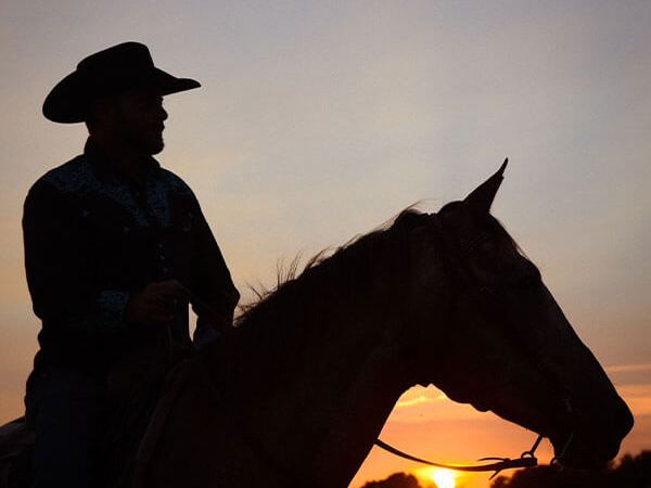 a man horseback riding with the sunset as a background at the stables at cedars of lebanon in nashville tn